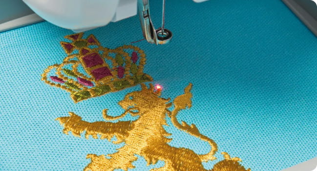 Red LED pointer on golden embroidered lion on blue fabric